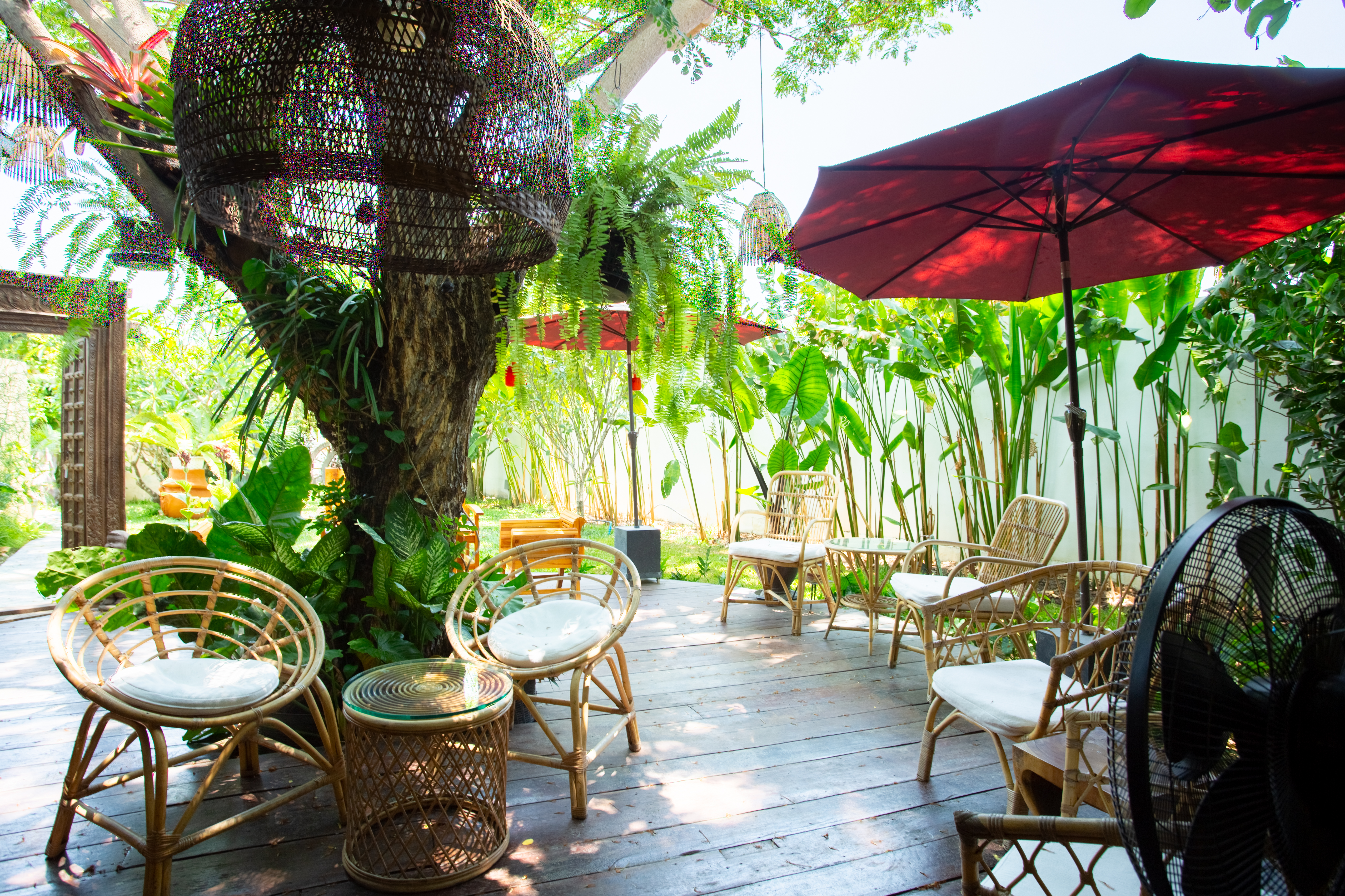 Garden seating beneath red umbrellas at Apsara