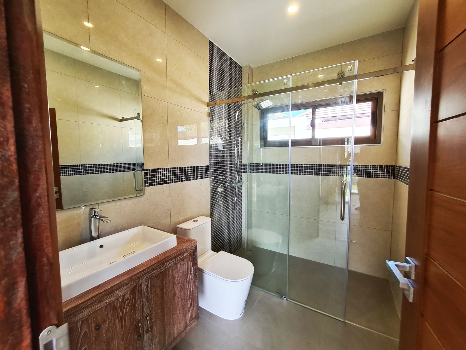 Second bathroom view with glass shower and natural wood door