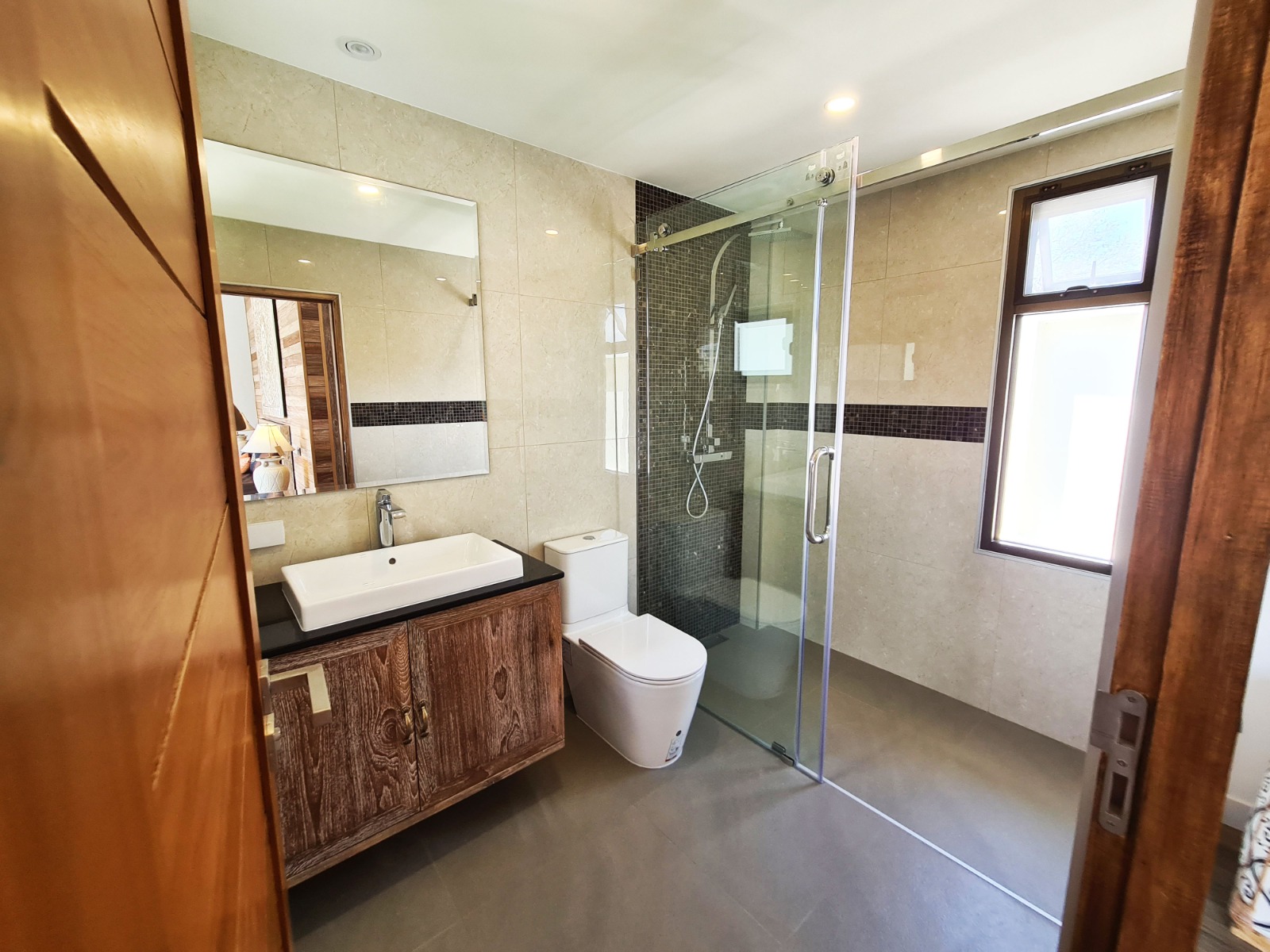 Bathroom with wood vanity, glass shower, and stone tile