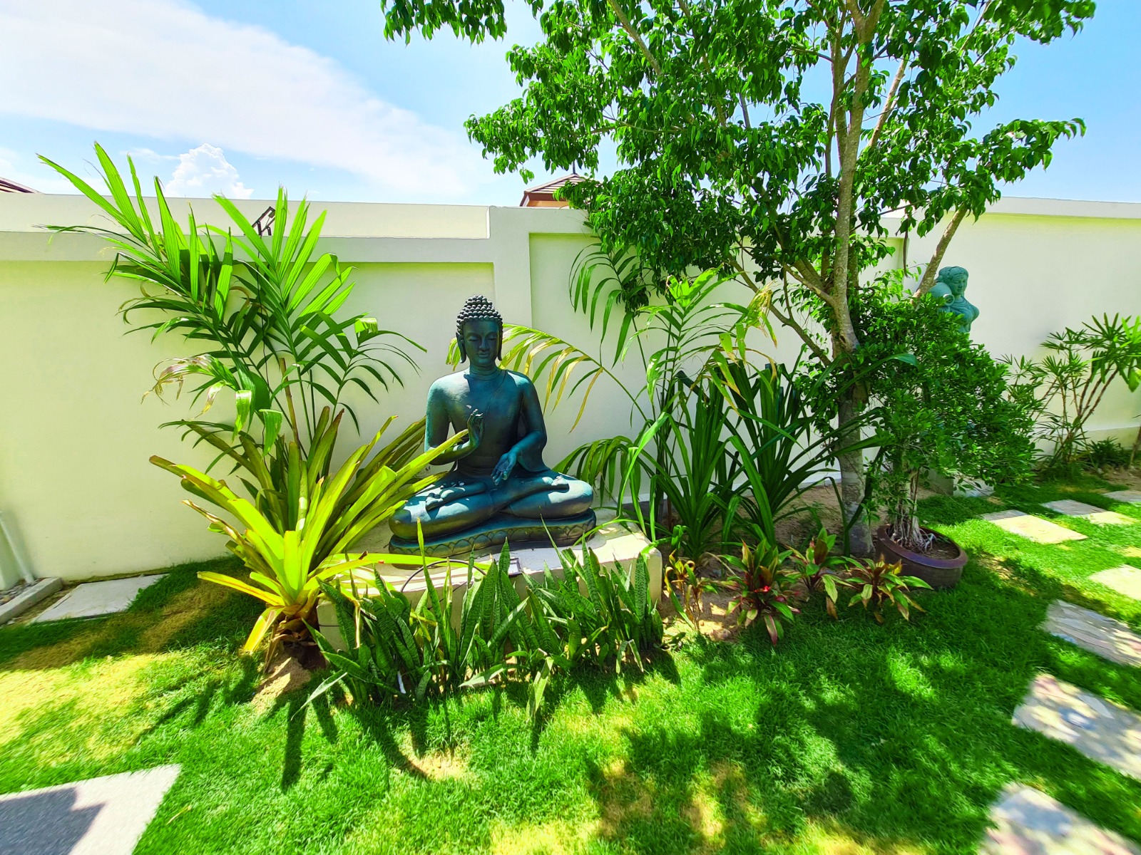 Quiet garden corner with Buddha sculpture and tropical planting