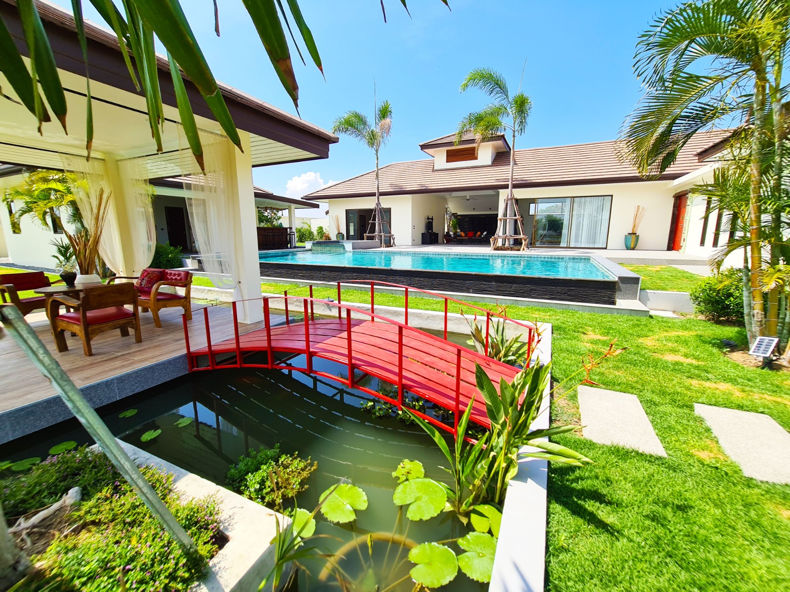 Red bridge, pond, pool, and tropical garden at Maprow Project