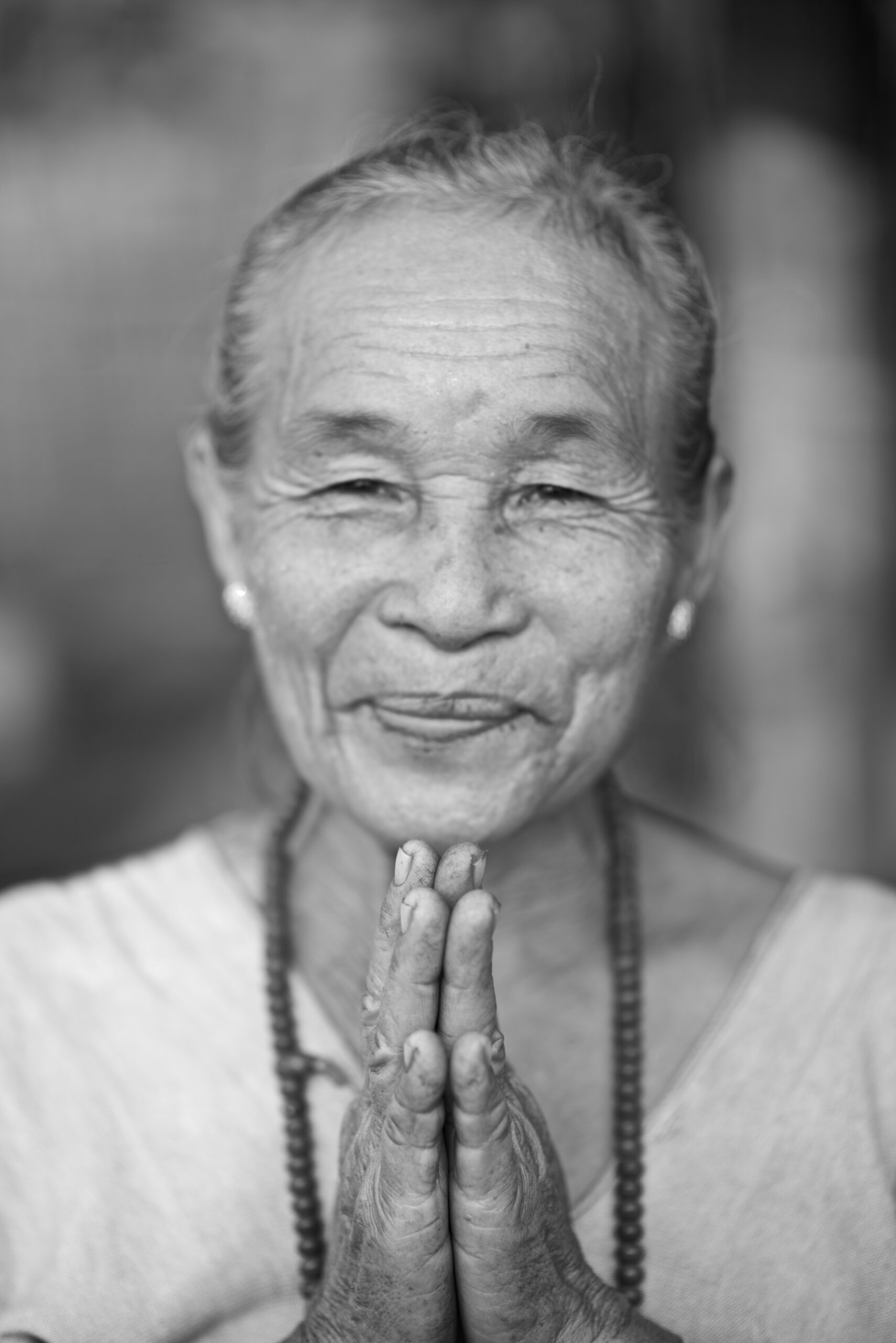 Elder woman greeting with hands in prayer